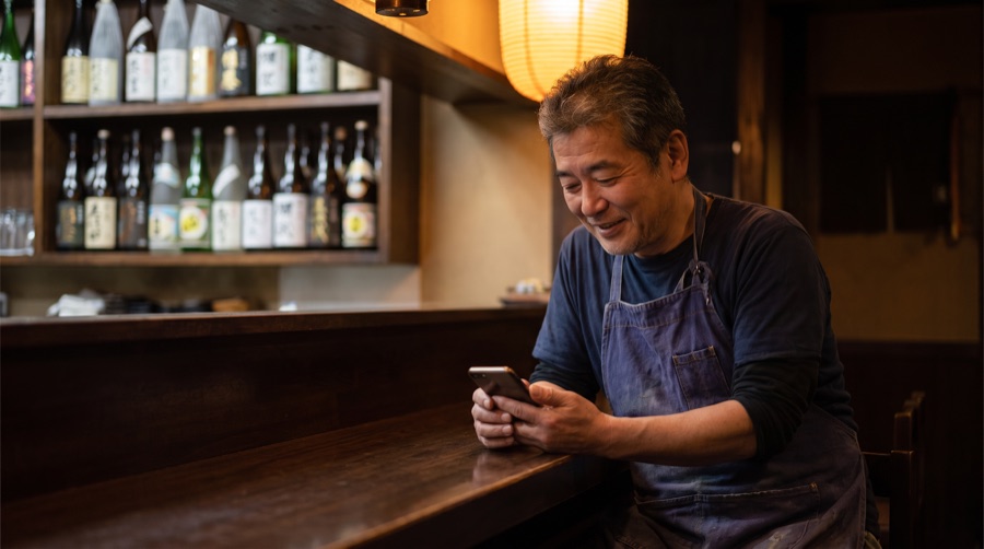 開店前の静かな時間にスマホで一言を打つ店主